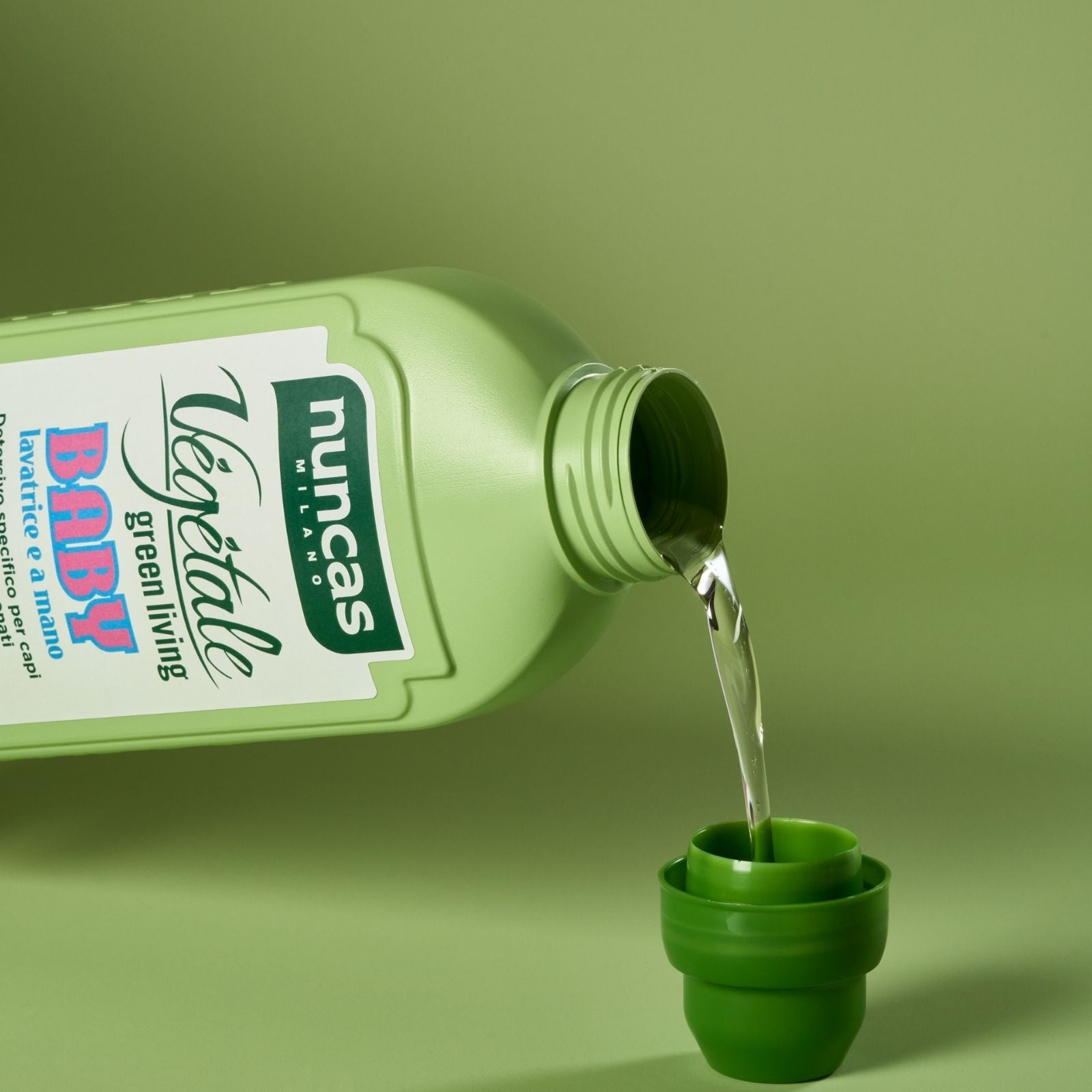Vegetale Detergente Specifico Baby Indumenti bambini e neonati fotografato mentre versa su sfondo neutro