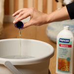 Un tappo di Winto Parquet viene diluito in acqua all'interno di un secchio per le pulizie