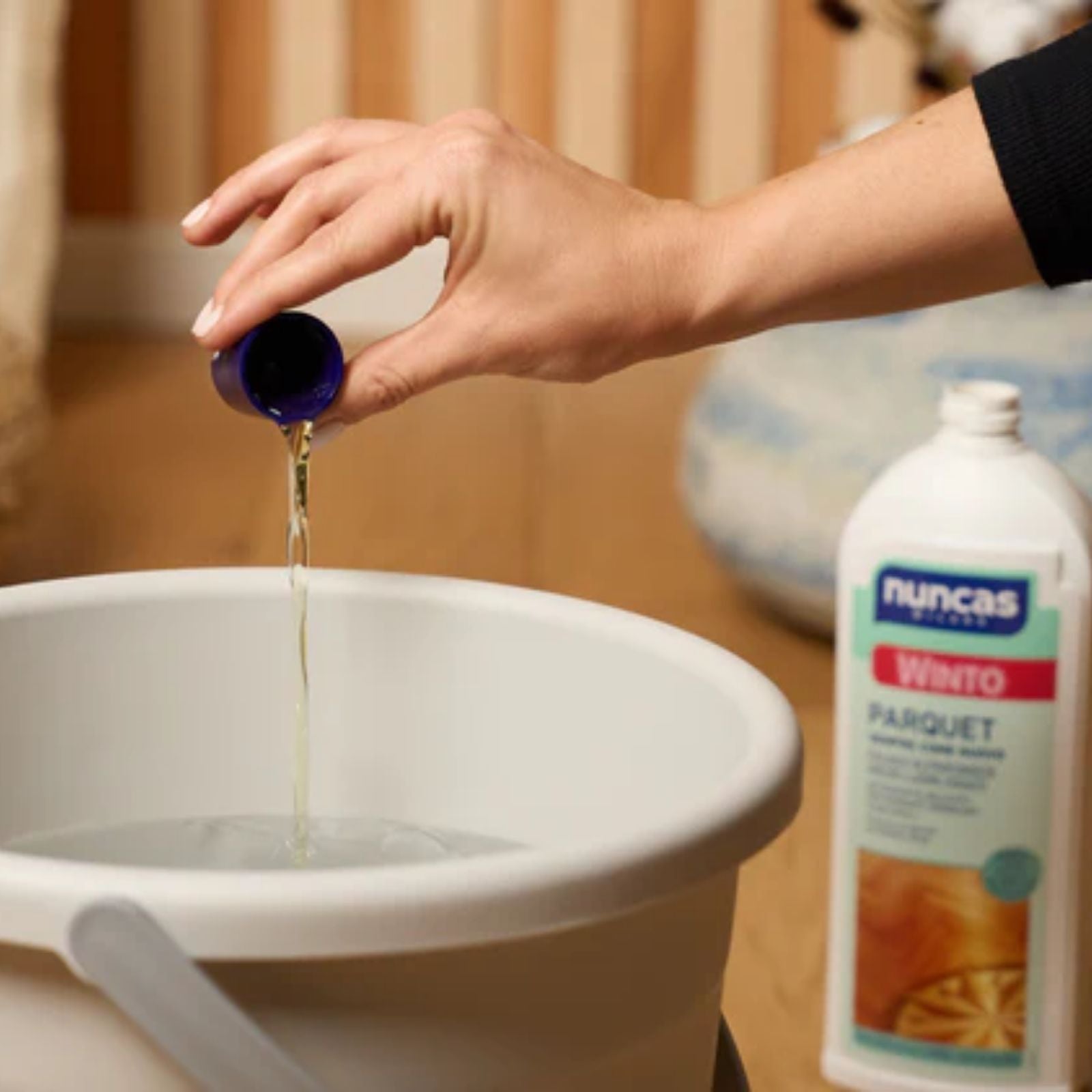 Un tappo di Winto Parquet viene diluito in acqua all'interno di un secchio per le pulizie